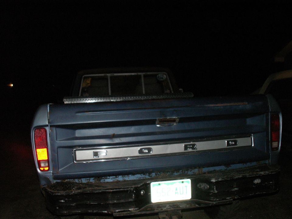 Rear view of a blue 1977 Ford F-250 pickup truck at night.