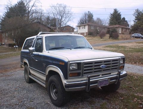 1986 Ford Bronco - This 1986 Ford Bronco is shown from the front three-quarter angle, parked on a gravel surface.