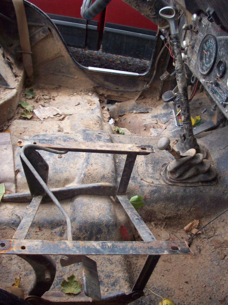 Interior of a dirty Jeep CJ5 showing floor, dashboard, and seat frame.