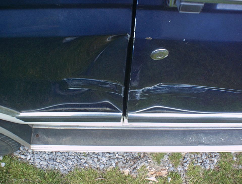 close-up of dented dark blue vehicle door and side panel