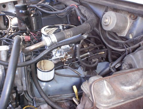 1986 Ford Bronco - Close-up view of an engine bay, focusing on the carburetor and related components.