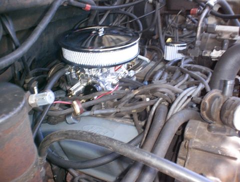 1986 Ford Bronco - Close-up view of a vehicle's engine bay, focusing on the carburetor and air intake system.