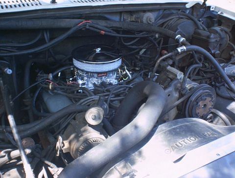 1986 Ford Bronco - Engine bay details with a chrome air cleaner and visible hoses and belts. Fan shroud reads 'CAUTION FAN'.