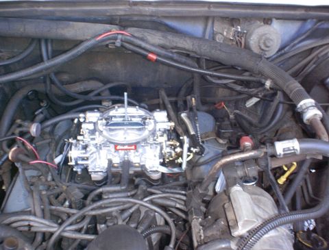 1986 Ford Bronco - Close-up view of a newly installed carburetor in a vehicle's engine bay, with visible "SuperMotors" branding at the bottom.