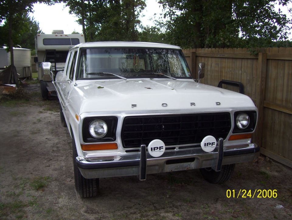 1978 Ford Bronco front view with IPF fog lights parked next to a wooden fence.