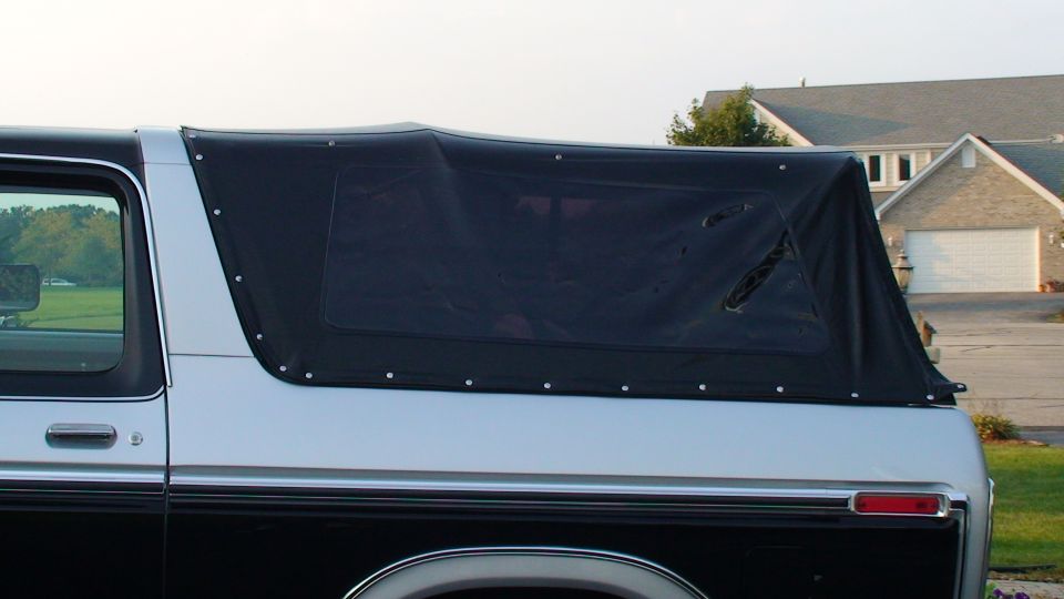 Black soft top with tinted window on white and black Ford Bronco outdoors