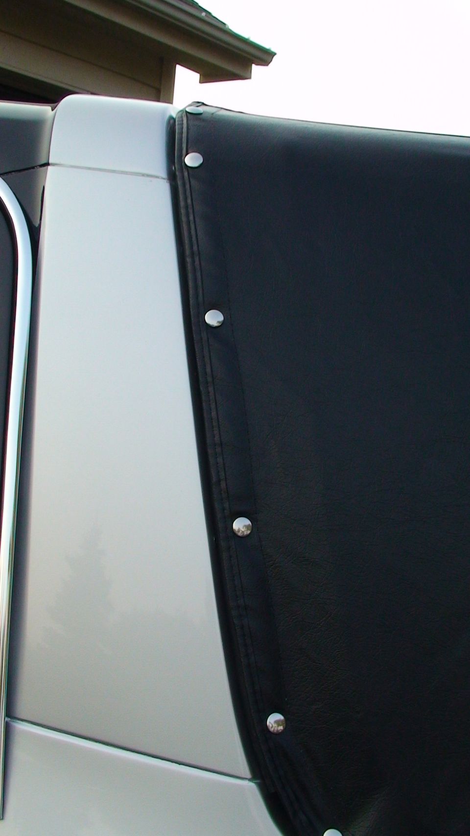 Black vinyl soft top edge with chrome snaps against silver body panel