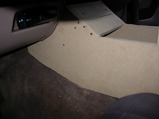 Cardboard console template test-fitted on vehicle carpet next to tan door panel