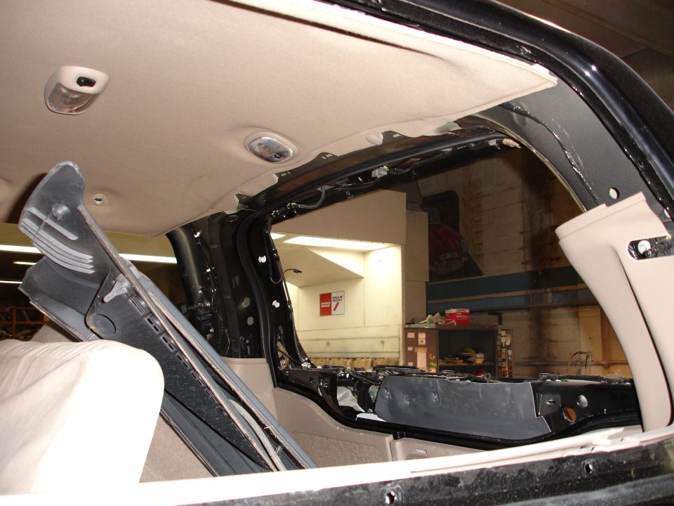 Interior of a black Ford Excursion with headliner removed, showing structural framework and wiring.