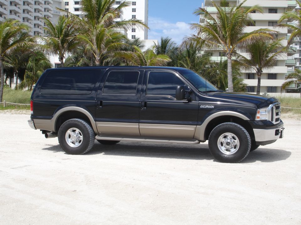 Black Ford Excursion SUV parked on a sandy beach.