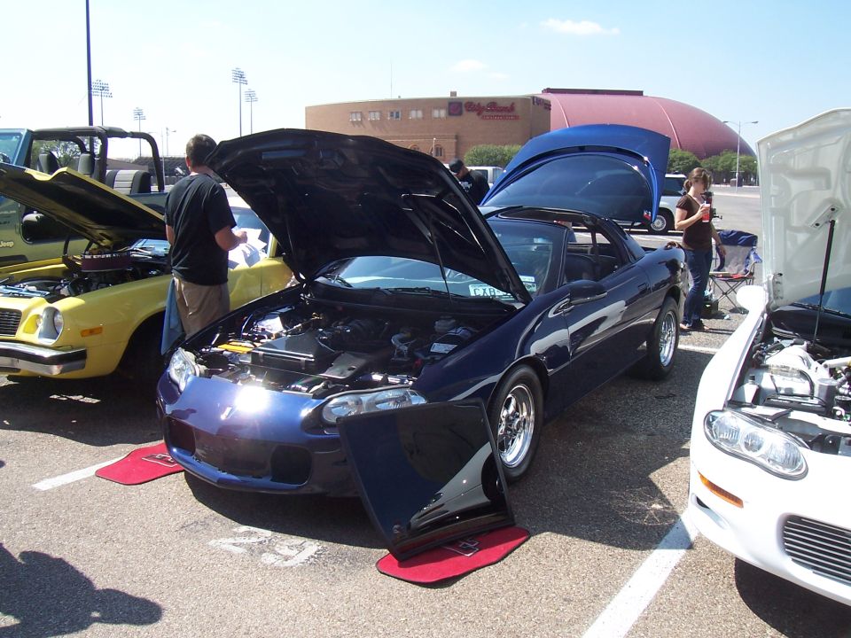 Photo of cars with open hoods at an outdoor car show