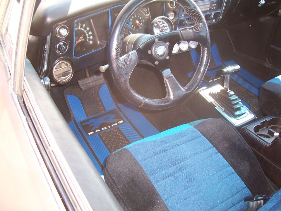 Photo of a car interior with gauges, shifter and blue floor mats