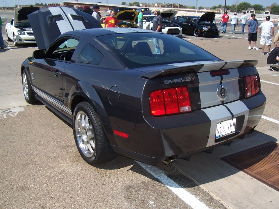 Dark gray Ford Mustang Shelby GT500 with silver racing stripes, rear view. License plate 414-VHM