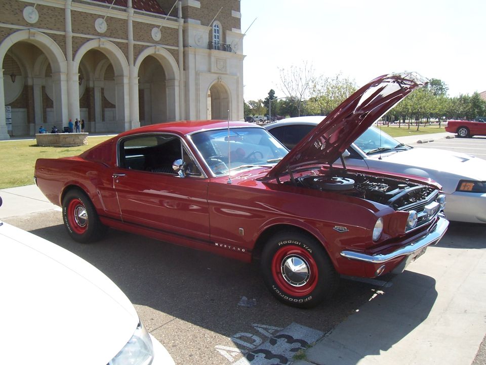 Red 1965 Ford Mustang fastback with hood open, parked next to a silver car