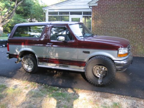 1996 Ford Bronco - A two-tone maroon and silver 1996 Ford Bronco is shown from a three-quarter front angle.