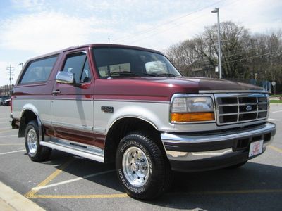 1996 Ford Bronco - Maroon and silver 1996 Ford Bronco SUV parked on asphalt, showing its front 3/4 view.