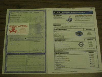1996 Ford Bronco - A Carfax vehicle history report and a certificate of title are laid out on a wooden surface.