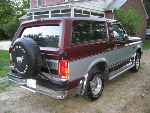 1996 Ford Bronco - This two-tone Ford Bronco is parked in a driveway next to a house.