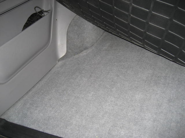 Interior cargo area with grey carpet and a plastic storage bin holding keys