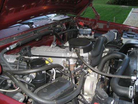 1996 Ford Bronco - The engine bay of a red 1996 Ford Bronco is shown with various components and hoses.