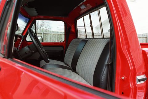 1979 Ford F-250 - The interior of a red pickup truck features a two-tone bench seat and a view through the windows.