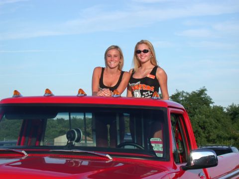 1979 Ford F-250 - Two women in Hooters shirts pose on the roof of a red 1979 Ford F-250 pickup truck.