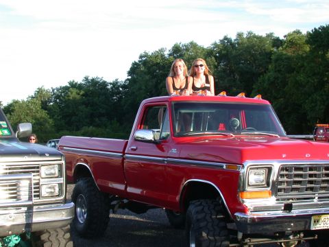 1979 Ford F-250 - Two women stand on the roof of a red 1979 Ford F-250 pickup truck parked outdoors.