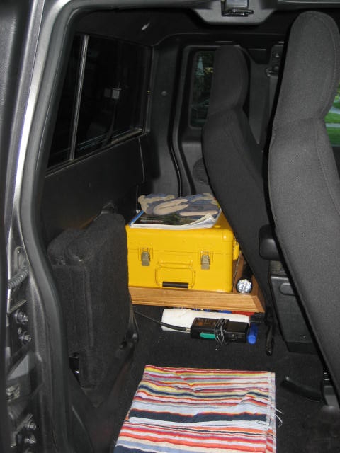 2004 Ford Ranger - Interior of a vehicle with a yellow toolbox and other items stored on the floor and a shelf.