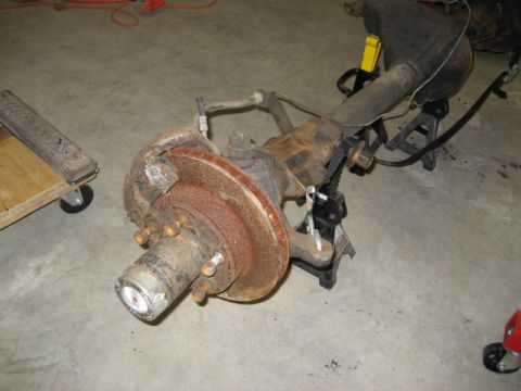1996 Ford Bronco - A front axle assembly, likely from a truck or SUV, is shown disassembled and supported by jack stands.