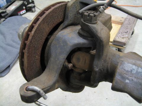 1996 Ford Bronco - Rusty front suspension knuckle with brake rotor and ball joint visible.