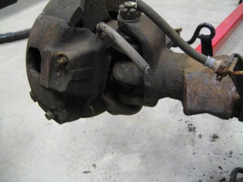 1996 Ford Bronco - Close-up of a heavily rusted brake caliper and axle assembly, showing wear and tear.