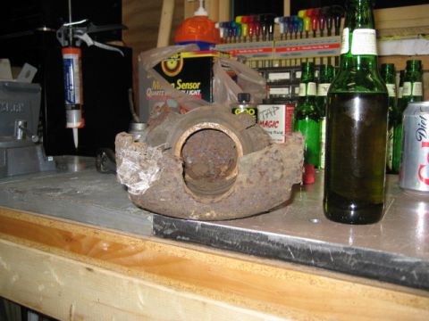 1996 Ford Bronco - A heavily corroded brake caliper rests on a metal surface, with various tools and beverages in the background.