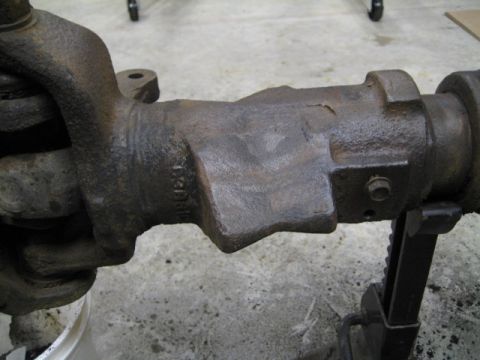 1996 Ford Bronco - Close-up of a heavily rusted axle part, showing casting details and a bolt attachment point.