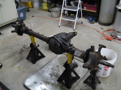 1996 Ford Bronco - Front axle assembly supported by jack stands in a garage setting.