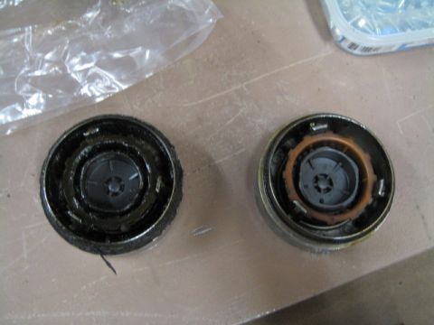 1996 Ford Bronco - Two automotive parts are shown on a flat surface, with a plastic bag and a container of screws in the background.