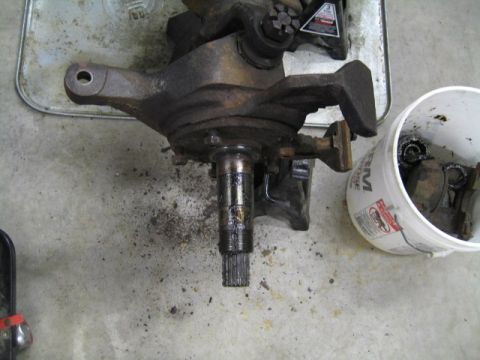 1996 Ford Bronco - A disassembled front wheel hub assembly sits on a concrete floor next to a bucket of used parts.