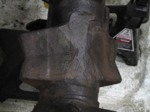 1996 Ford Bronco - Close-up of a heavily rusted metal component supported by a jack stand.