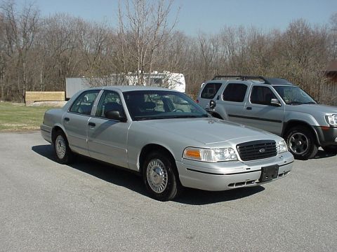 2000 Ford Crown Victoria - A silver 2000 Ford Crown Victoria sedan is parked on asphalt, with an SUV visible to its right.