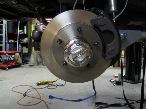 1996 Ford Bronco - A close-up view of a vehicle's front brake assembly, focusing on the rotor and a hubcap that reads "Ford".
