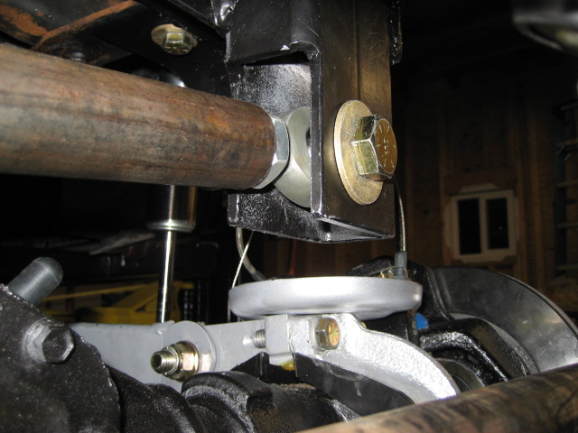 Close-up of vehicle suspension with rusty pipe, black bracket, and silver components