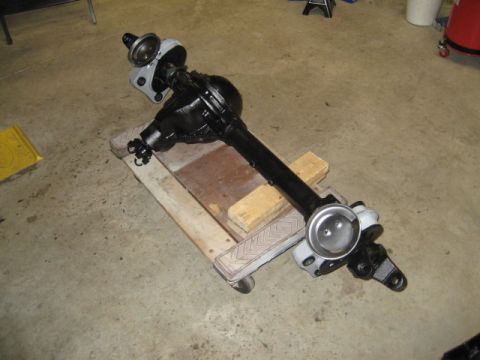 1996 Ford Bronco - A black Ford Bronco front axle assembly is shown resting on wooden blocks with casters.