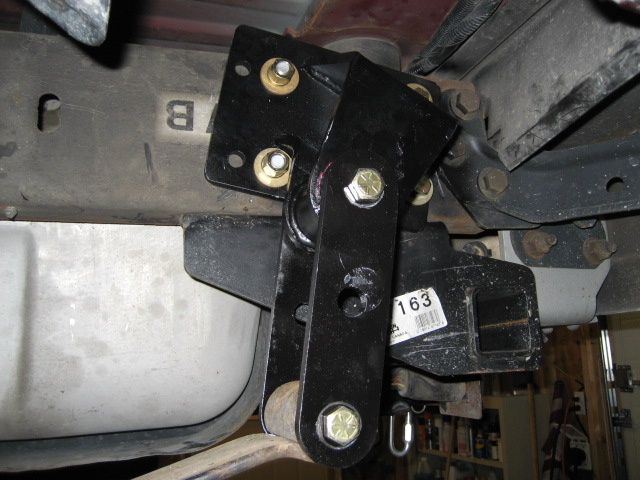 Black metal suspension component attached to vehicle frame near fuel tank