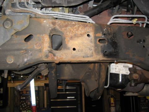 1996 Ford Bronco - Close-up of rusted vehicle frame and suspension components, with a visible label.