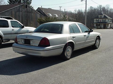 2000 Ford Crown Victoria - A silver 2000 Ford Crown Victoria sedan is parked next to a white SUV.