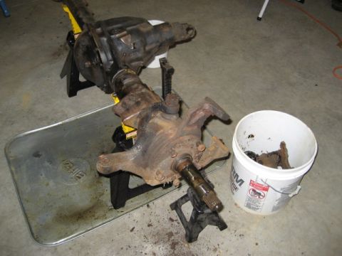 1996 Ford Bronco - Front axle and differential assembly, likely from a truck or SUV, is disassembled and supported by jack stands.