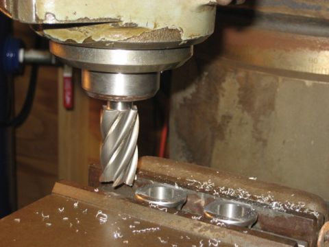1996 Ford Bronco - A milling machine is actively cutting two small metal components, with metal shavings scattered around the work area.