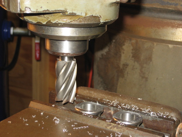 Milling machine cutting two small metal parts with shavings on the surface