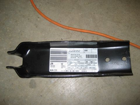 1996 Ford Bronco - A black metal automotive part with a detailed label is shown on a concrete floor with an orange cord nearby.