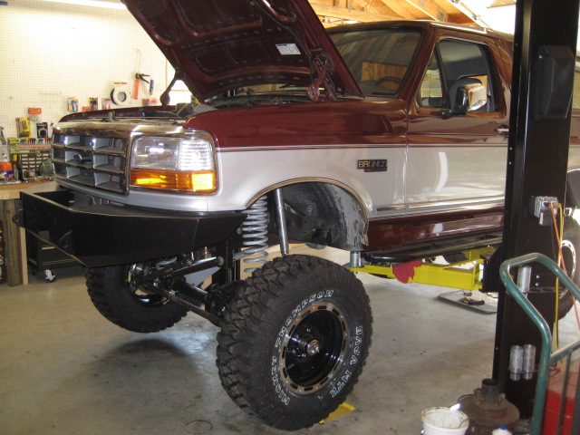 1996 Ford Bronco with hood up, on a lift, showing custom bumper and suspension