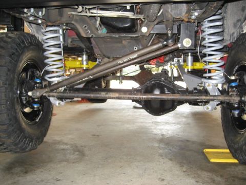 1996 Ford Bronco - A close-up view of a vehicle's undercarriage reveals custom suspension and drivetrain parts.